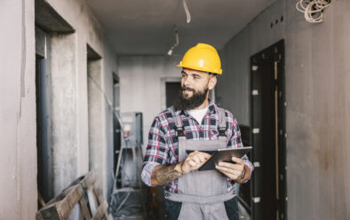 A dedicated worker using tablet for work in a building in a construction process.